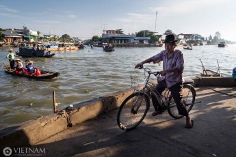 Grandfather biking along a floating market